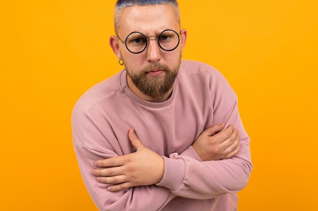 Junger starker Mann mit kurzen schwarzen Haaren wird isoliert auf orange Hintergrund eingefroren