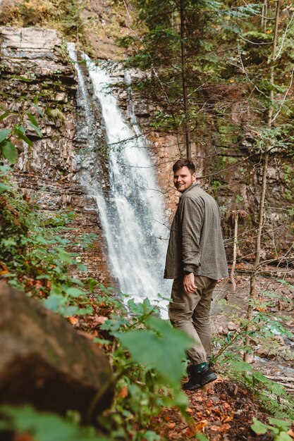 Junger starker Wanderer, der den Wasserfallkopierraum schaut