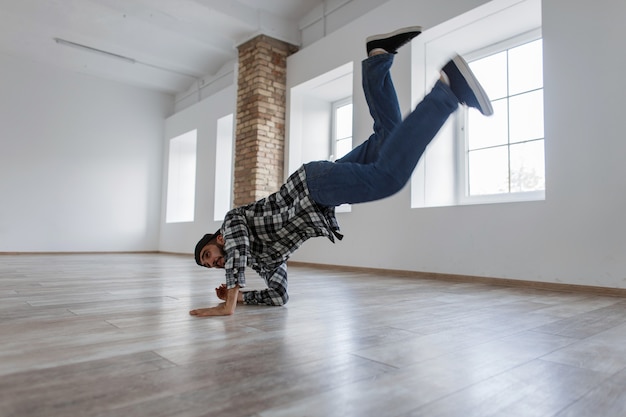 Junger stilvoller Tänzertyp mit Jeans und Hemd, die in einem hellen Tanzstudio tanzen