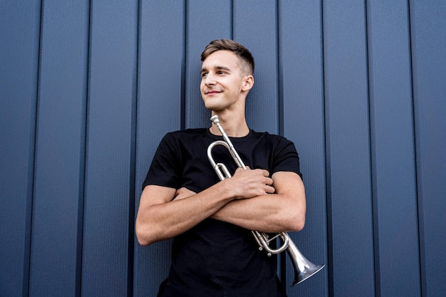 Junger Straßenmusiker, der die Trompete nahe der großen blauen Wand spielt