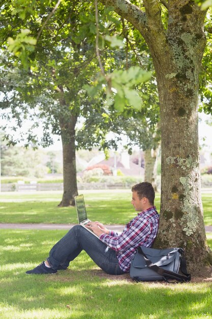 Junger Student, der draußen seinen Laptop verwendet