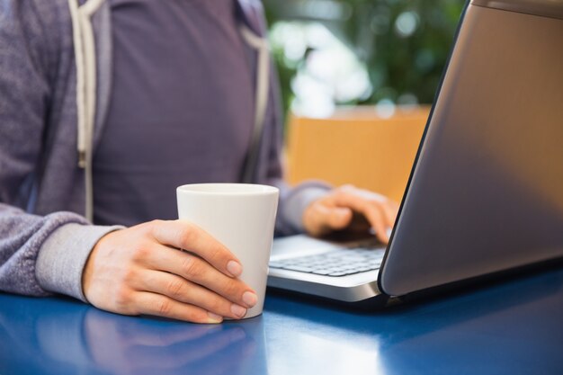 Junger Student, der seinen Laptop im Café verwendet