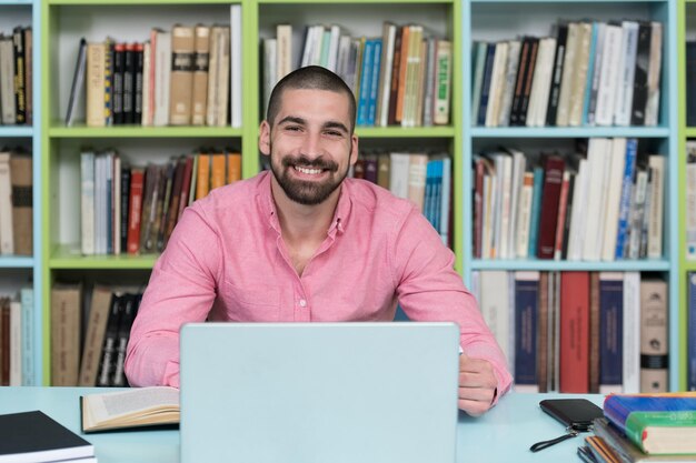 Junger Student, Der Seinen Laptop In Einer Bibliothek Verwendet