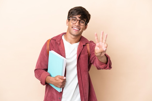 Junger Student kaukasischer Mann isoliert auf ockerfarbenem Hintergrund glücklich und zählt drei mit den Fingern
