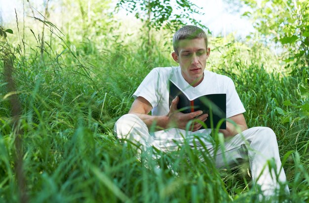 Junger Student mit Buch im Freien