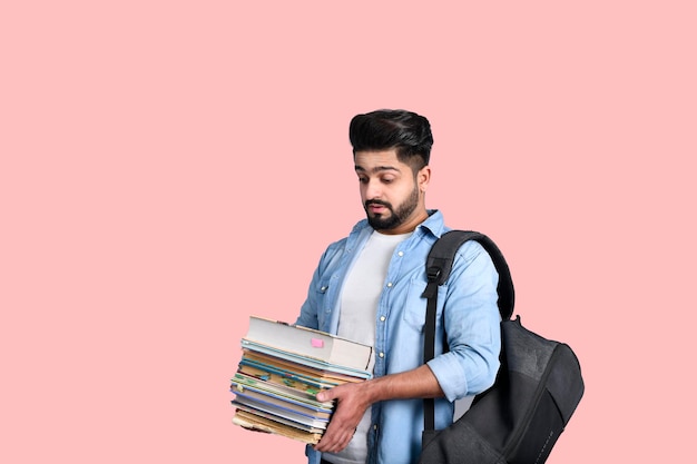 Junger Student mit Rucksack, der Bücher hält, legeres Outfit, indisches pakistanisches Modell