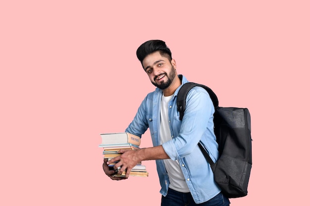 Junger Student mit Rucksack, der Bücher hält, legeres Outfit, indisches pakistanisches Modell