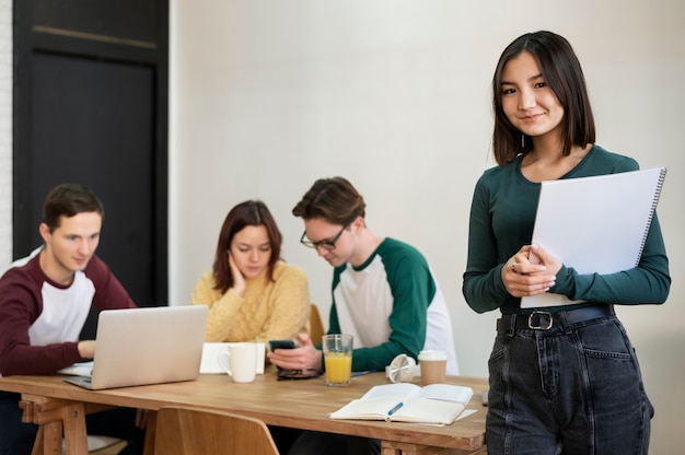 Foto junger student während des gruppenstudiums posiert am schreibtisch