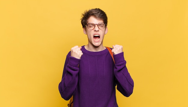 Junger Studentenjunge mit einer Schultasche gegen orange Wand