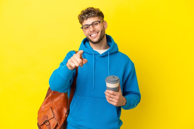 Junger studentischer blonder mann lokalisiert auf gelbem hintergrund, der front mit glücklichem ausdruck zeigt