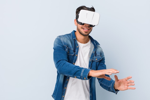 Junger südasiatischer Mann, der mit Gläsern der virtuellen Realität spielt