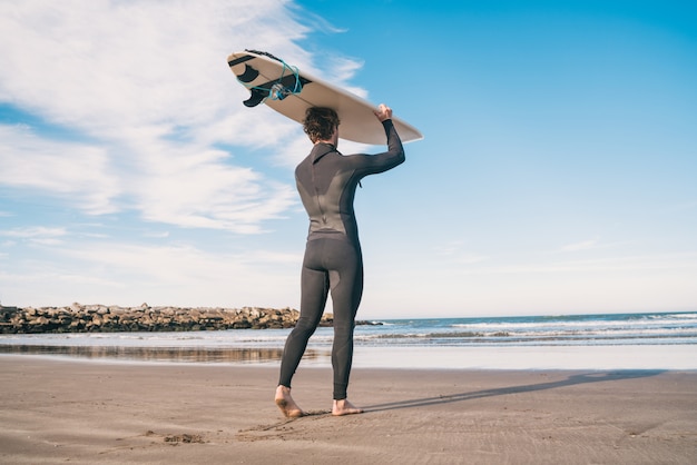 Junger Surfer hält sein Surfbrett hoch