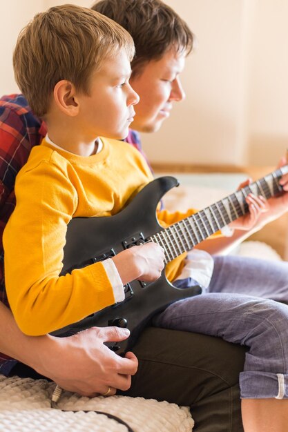 Junger tausendjähriger Vater und süßer Sohn, der E-Gitarre spielt