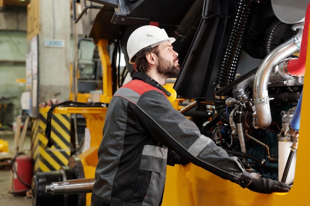 Junger Techniker oder Mechaniker im Hardhat, der Industriemaschine bereitsteht