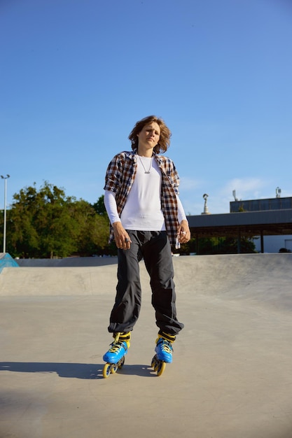 Junger Teenager mit Rollerblades macht Stunt auf Betonrampe im Skatepark