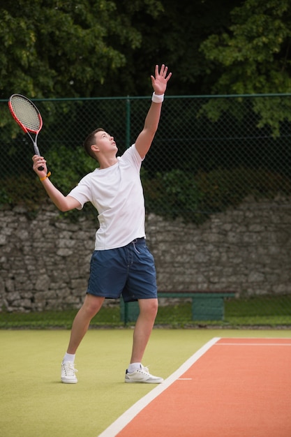 Junger Tennisspieler im Begriff zu dienen