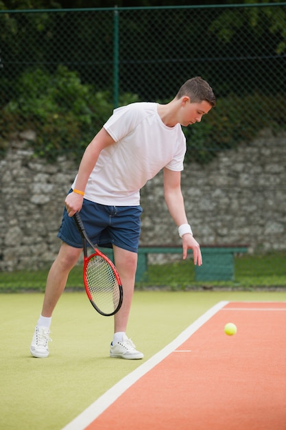 Junger Tennisspieler im Begriff zu dienen