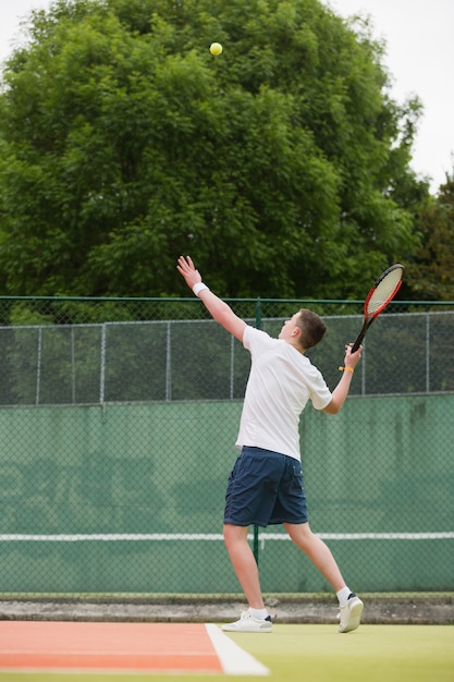 Junger Tennisspieler im Begriff zu dienen