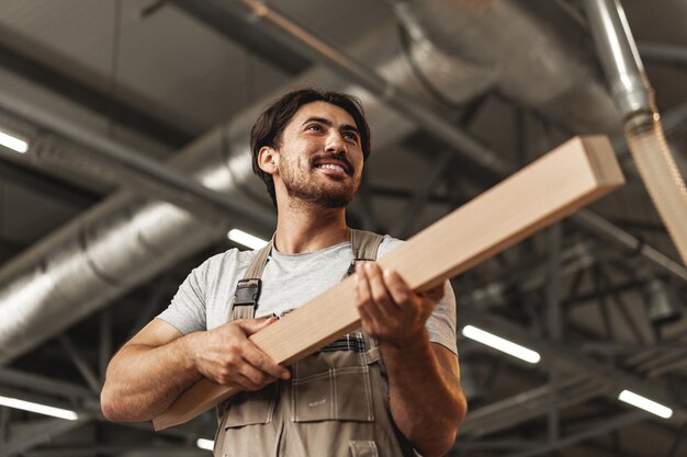 Junger Tischler sucht und wählt Holzbretter in der Werkstatt einer Tischlerholzfabrik aus