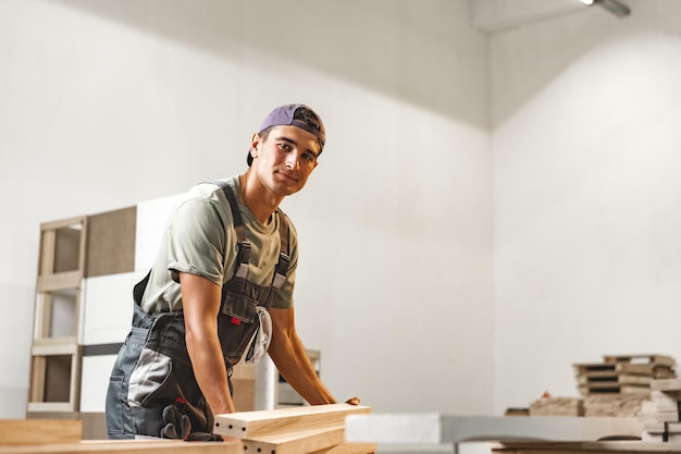 Junger Tischler sucht und wählt Holzbretter in der Werkstatt einer Tischlerholzfabrik aus
