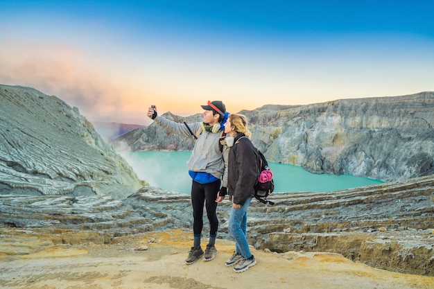 Junger Touristenmann und -frau stehen am Rand des Kraters des Ijen-Vulkans oder des Kawah Ijen auf