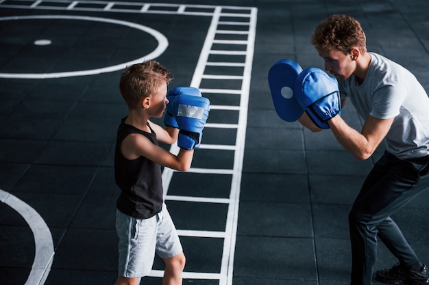 Junger Trainer unterrichtet Kinderboxsport im Fitnessstudio.