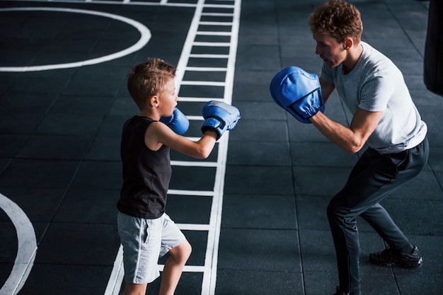 Junger Trainer unterrichtet Kinderboxsport im Fitnessstudio.