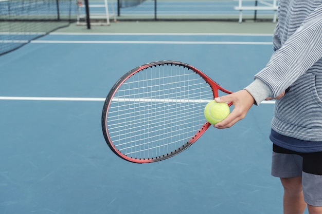 Junger Tweenjungen-Tennisspieler auf blauem Gericht im Freien