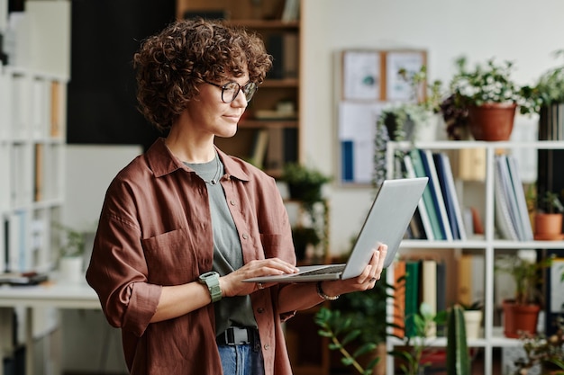 Junger überzeugter weiblicher Programmierer des Brunette mit Laptop