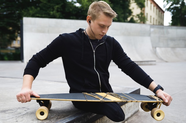 Junger und motivierter behinderter Kerl mit einem Longboard im Skatepark