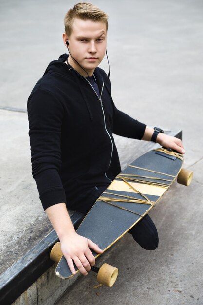 Junger und motivierter Behinderter mit einem Longboard in einem Skatepark