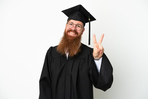 Junger Universitätsabsolvent rötlicher Mann isoliert auf weißem Hintergrund lächelnd und Victory-Zeichen zeigend