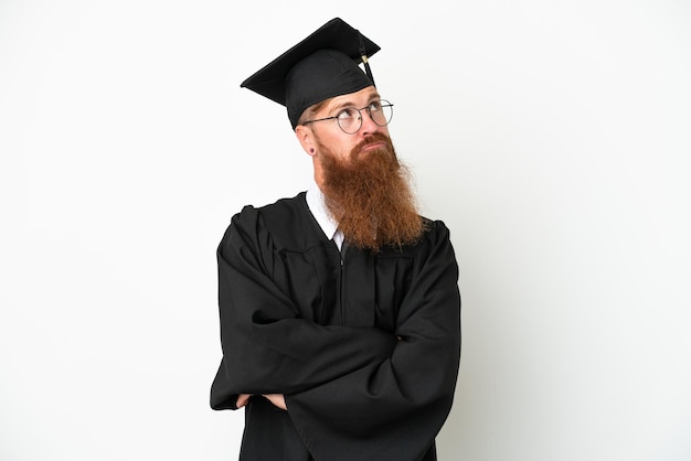 Junger Universitätsabsolvent rötlicher Mann isoliert auf weißem Hintergrund und nachschlagend