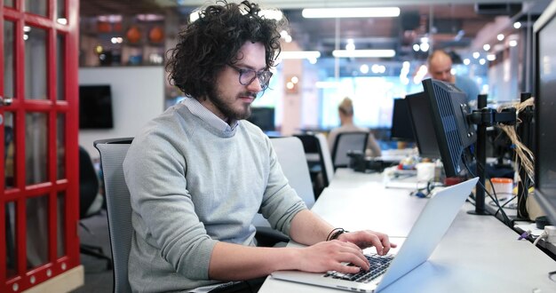 Foto junger unternehmer, freiberufler, der mit einem laptop im coworking space arbeitet