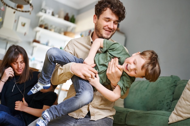 Junger Vater, der Spaß mit Liedern hat und zu Hause lacht Glückliche Familie, die Zeit zusammen verbringt