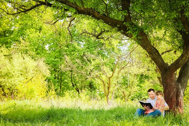 Junger Vater mit einer kleinen Tochter, die die Bibel liest