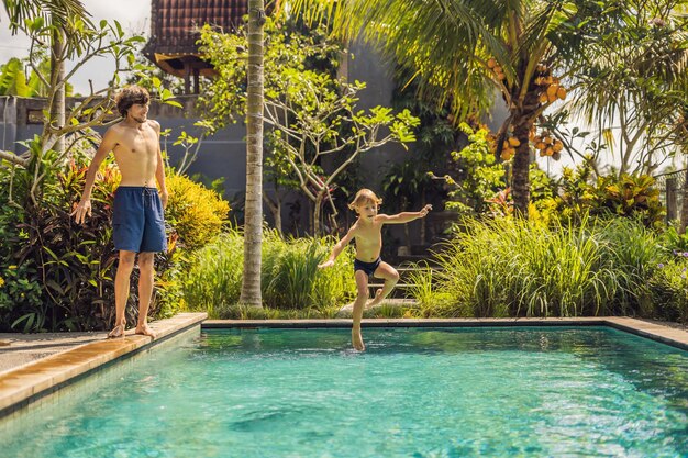 Junger Vater mit kleinem Sohn, der im Pool spielt