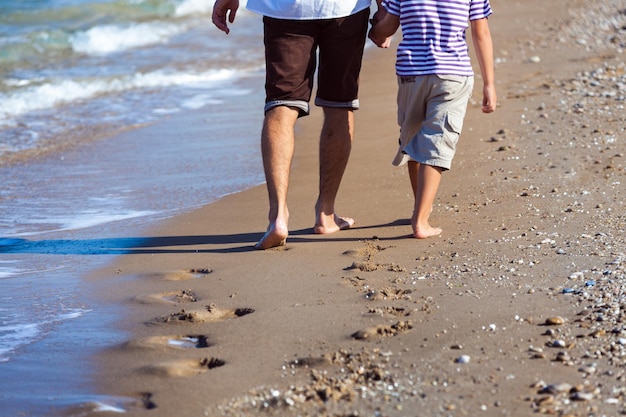 Junger Vater mit Sohn auf Hintergrund des sandigen Strandes