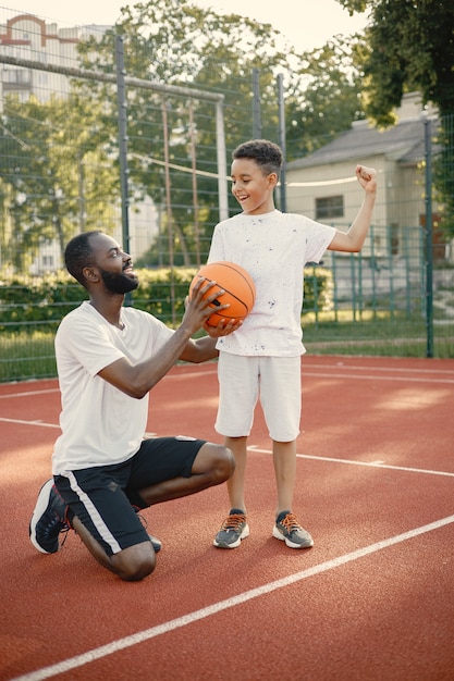 Junger Vater und sein Sohn stehen auf Basketballplatz in der Nähe des Parks