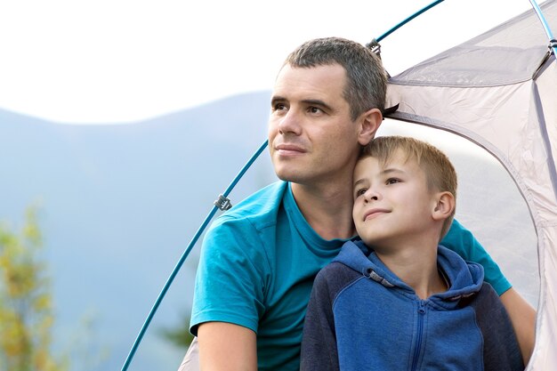 Junger Vater und sein Sohn wandern zusammen in den Sommerbergen. Aktives Familienreisekonzept.
