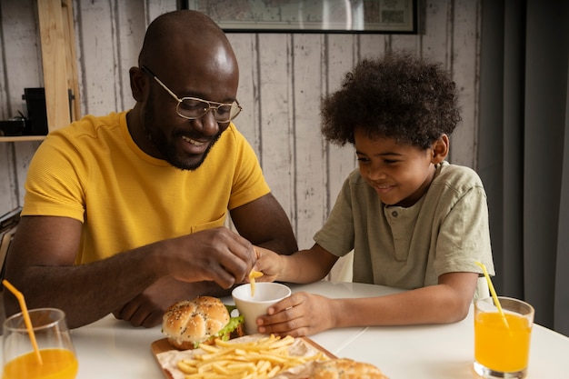 Junger Vater und Sohn essen zusammen Burger und Pommes