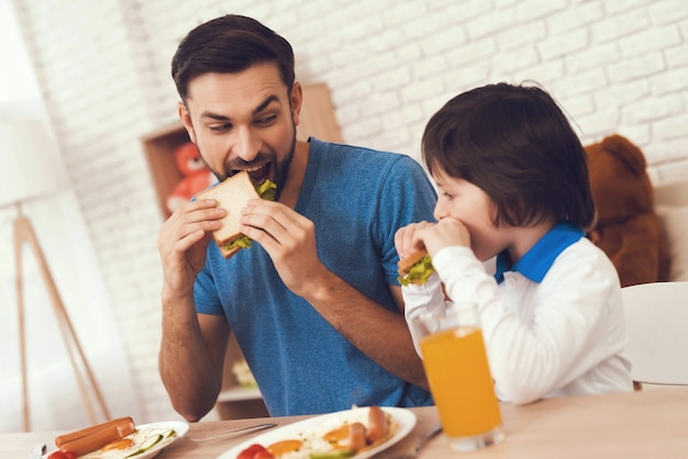 Junger Vater und Sohn frühstücken.