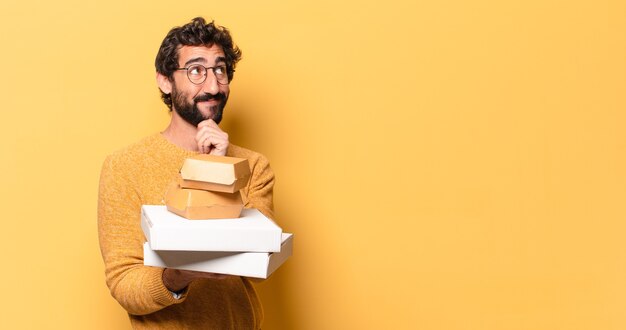 Junger verrückter bärtiger Mann, der Fastfood mit einem Kopienraum wegnehmen