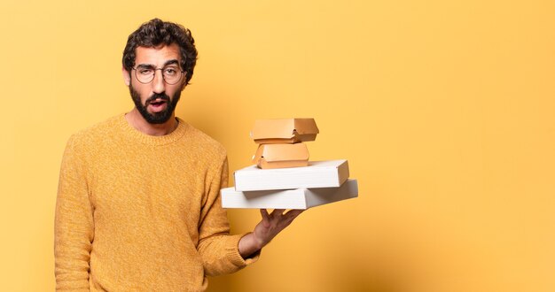 Junger verrückter bärtiger Mann, der Fastfood mit einem Kopienraum wegnehmen