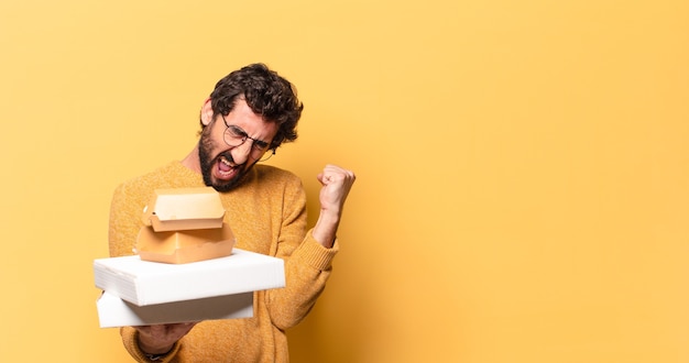 Junger verrückter bärtiger Mann, der Fastfood mit einem Kopienraum wegnehmen