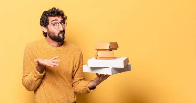 Junger verrückter bärtiger Mann, der Fastfood mit einem Kopierraum wegnimmt