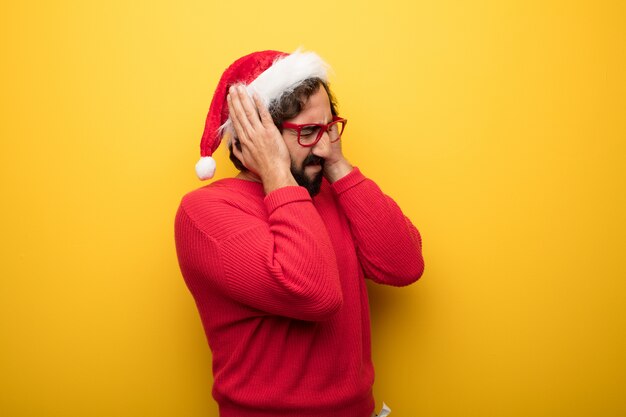 Junger verrückter bärtiger Mann, der rote Gläser und Weihnachtsmann-Hut trägt