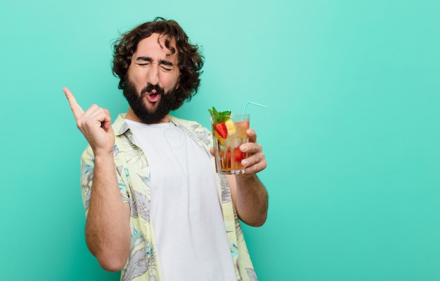 Junger verrückter bärtiger Mann mit einem Cocktail. Tourist