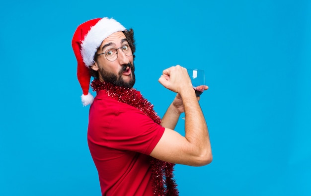 Junger verrückter bärtiger Mann mit Sankt-Hut. Weihnachtskonzept