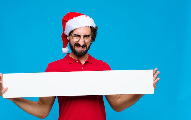 Junger verrückter bärtiger Mann mit Sankt-Hut. Weihnachtskonzept